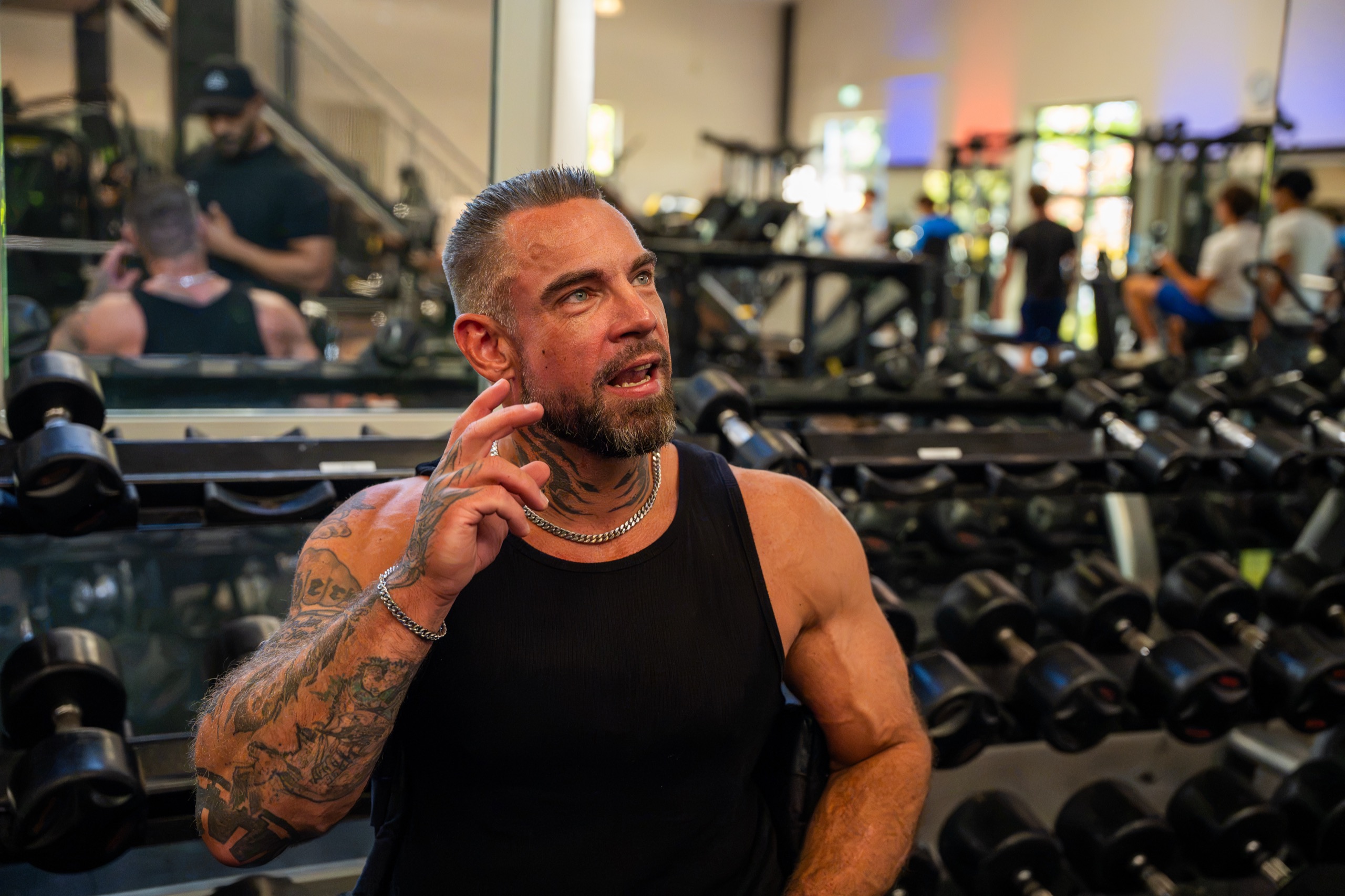Kim-Andre Brüske im Gespräch im Fitnessstudio, hinter ihm die Hantelablage